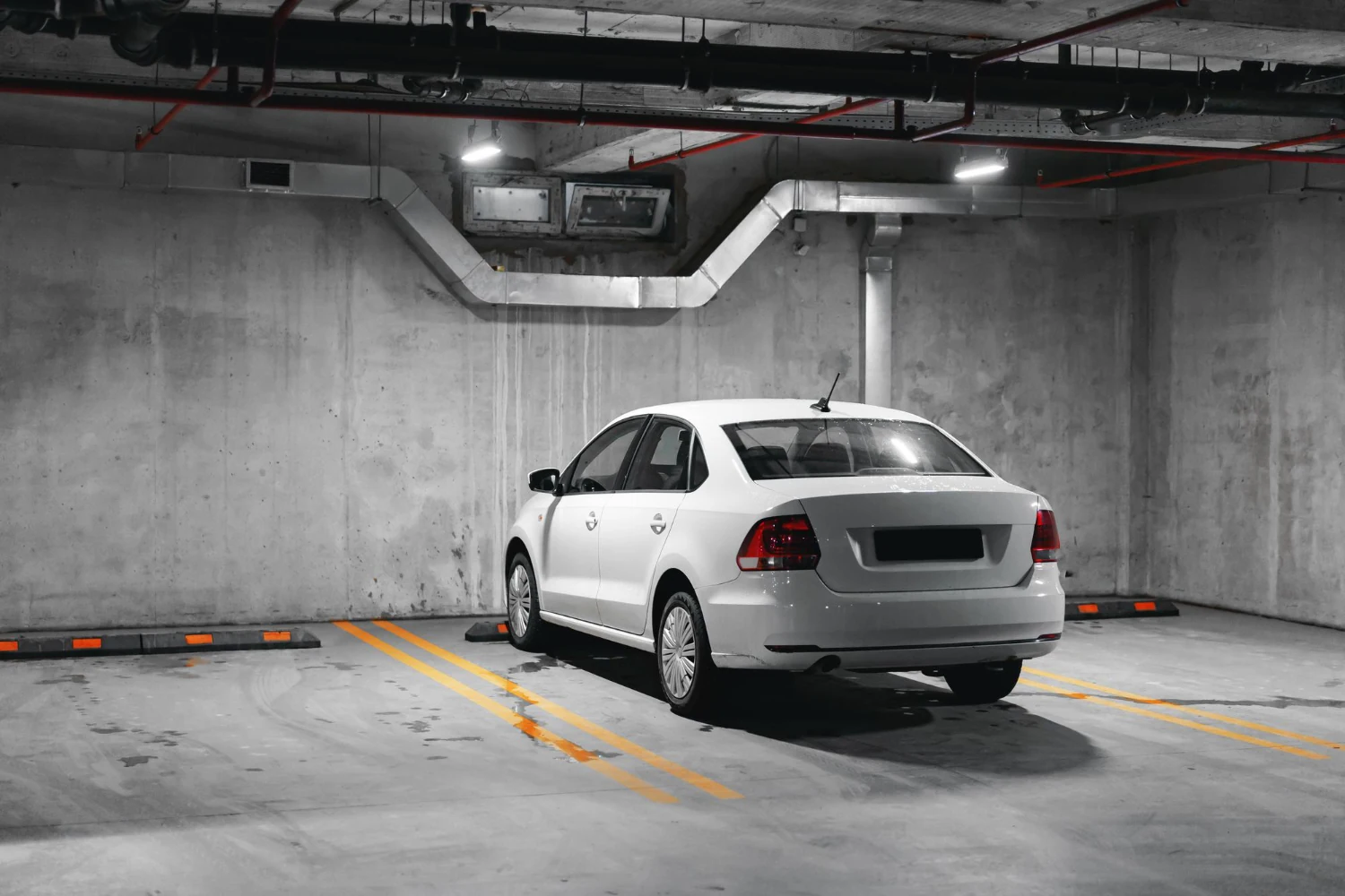 Betonarme yer altı otoparkında park edilmiş beyaz otomobil